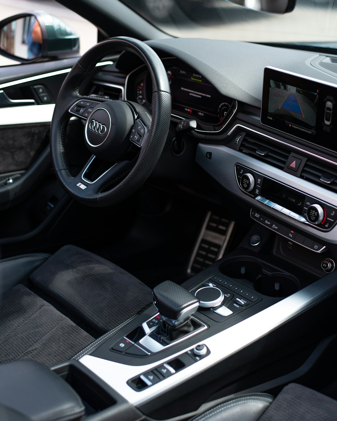 Modern car cockpit with digital dashboard and leather steering wheel.