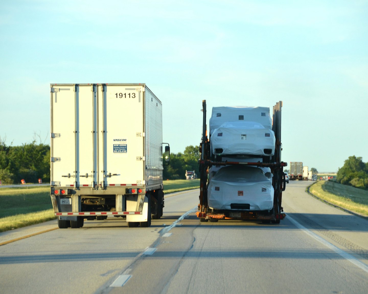 Two commercial trucks drive down a highway.