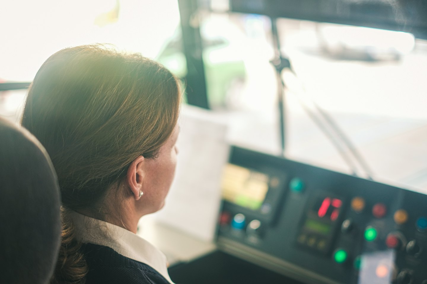 Woman drives a bus, looking at the road ahead.