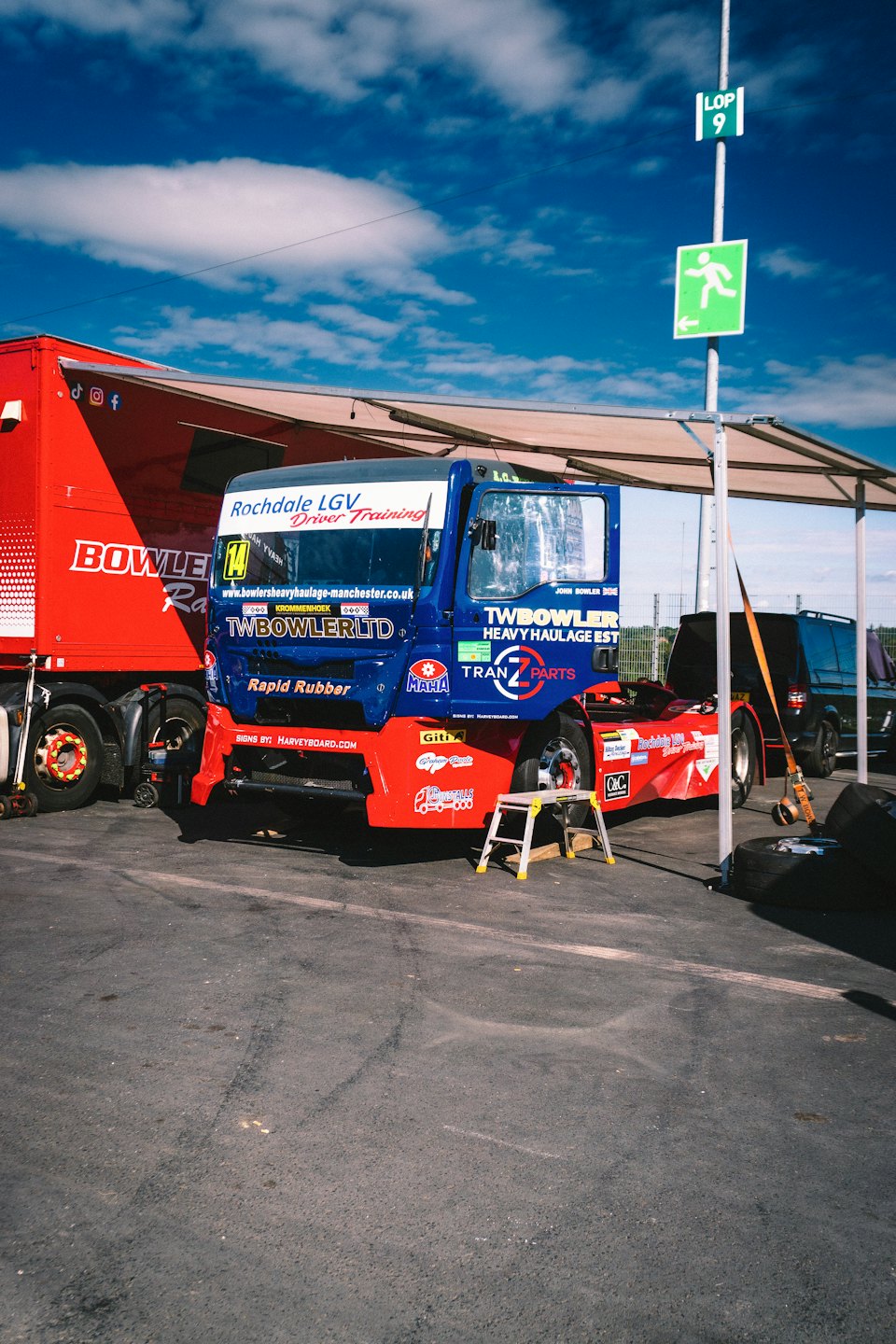 Blue and red racing truck parked under a canopy.