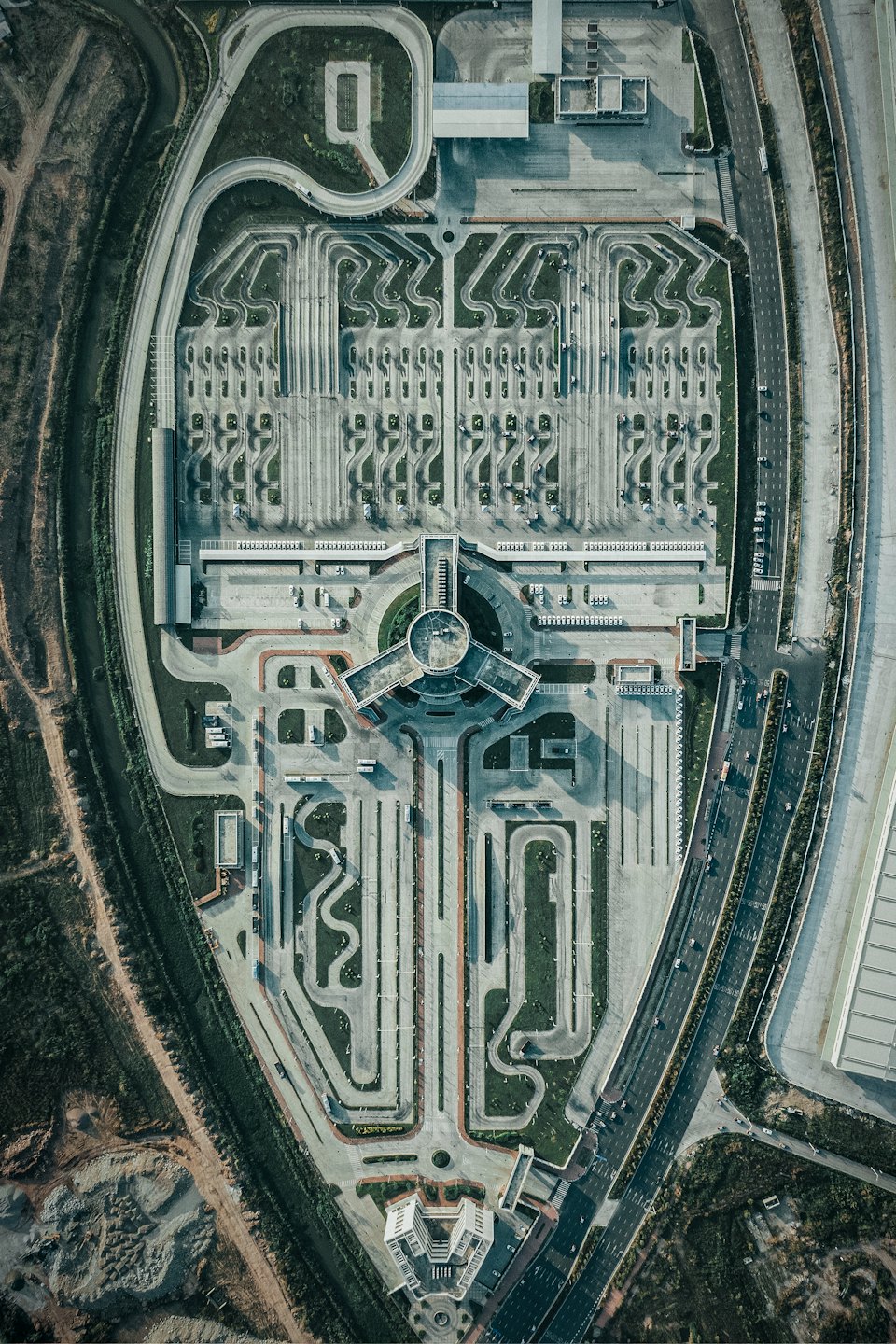 Modern driving training facility with concrete tracks and adjacent highway.